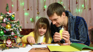 爸爸帮助女儿粘在圣诞节手工制作的物品元素上笑声29秒视频
