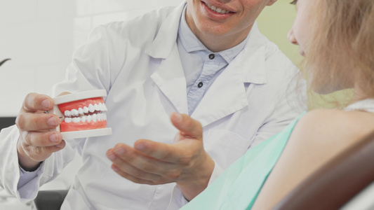 男性牙医有牙科假牙向病人解释牙齿护理视频