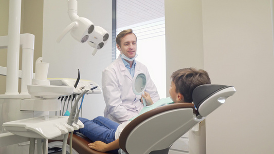 快乐的小男孩和他的牙医笑着对着镜头微笑视频