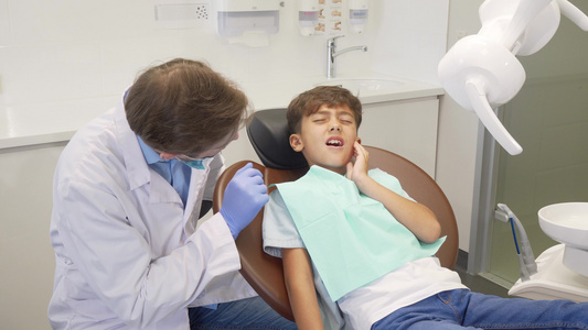 小男孩有小牙痛在牙齿检查时坐在牙科椅上视频