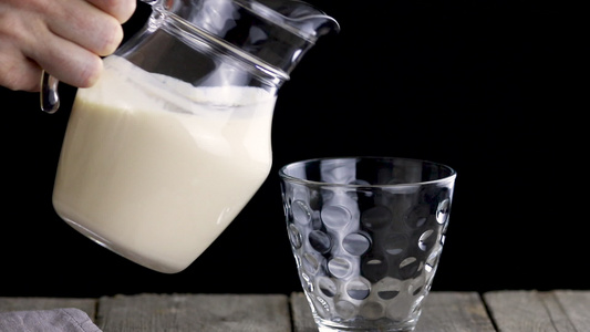 人将发酵的烤奶从一个罐子倒到玻璃杯中视频