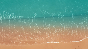 4K航拍海面上翻涌着的浪花拍打在沙滩上14秒视频
