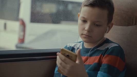 一个小男孩乘公共汽车穿越城市的特写镜头他在智能手机视频