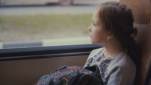 年轻美丽的女孩乘着学校包在移动校车的客车上向窗外看28秒视频