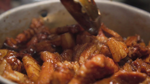 有人用勺子搅拌五花肉在锅上打滚与棕色酱汁混合平移拍摄12秒视频