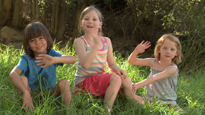 孩子们坐在草地对着镜头挥手5秒视频