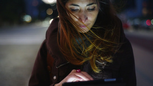 夜晚的女子走在路边使用数字平板电脑16秒视频
