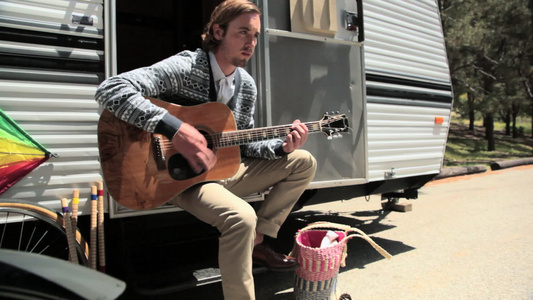 大篷车旁弹吉他的年轻人视频