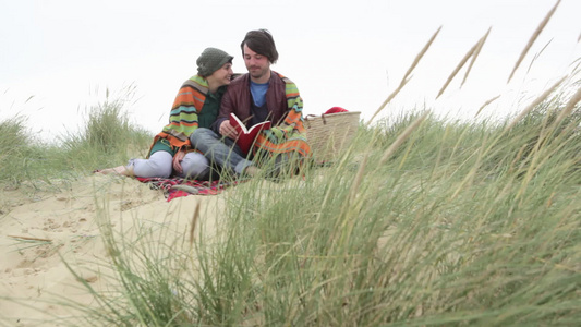 一对年轻夫妇在裹着毯子的沙丘上视频
