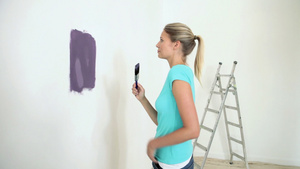 年轻女子在墙上画紫色油漆10秒视频