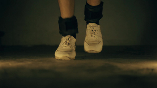穿着白色运动鞋和黑色脚踝重量的腿部特写镜头视频