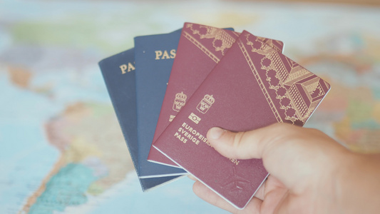 手持瑞典和美国护照在彩色世界地图前视频