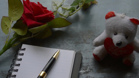 空白页笔记本钢笔质朴的金属地板背景上的一朵美丽的红玫瑰视频