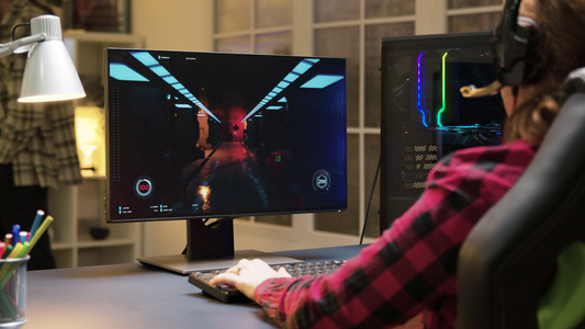 女用耳机坐在游戏椅上在计算机上玩电子游戏视频