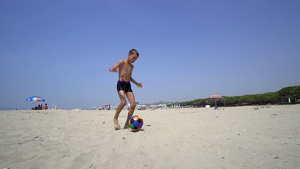 年轻男孩踢足球踢足球球赤脚在沙沙滩上跑13秒视频