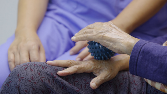 年长妇女为锻炼手指手掌手和脚的肌肉做橡皮球视频