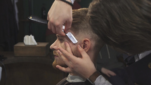 被理发师用剃刀刮的剃胡须剪得一脸英俊的男人9秒视频