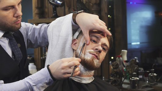 英俊的年轻人在理发店刮胡子时剃胡子视频