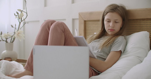 疲惫而无聊的女学生躺在床上带着练习本在笔记本电脑上13秒视频