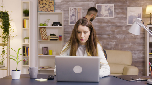 在家庭办公室用笔记本电脑工作的年轻美丽的年轻女子视频