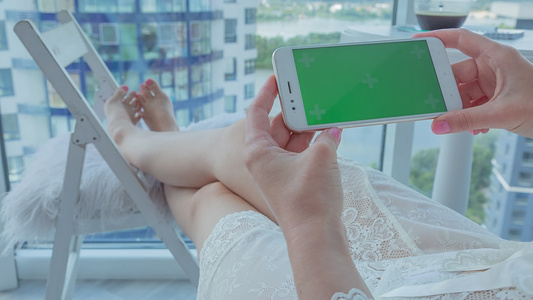 年轻女子拿着绿色屏幕的智能手机视频
