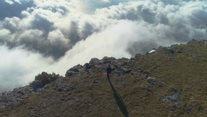 有背包的徒步男子正在行走站在云端高地的陡峭边缘举起手来32秒视频