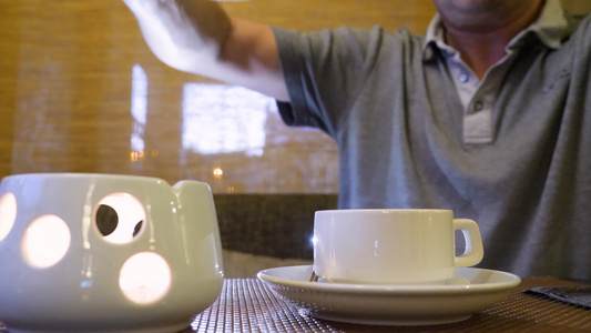 男人拿茶壶喝茶然后把热茶倒在餐桌上的杯子里视频