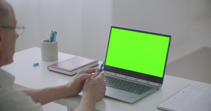 退休男子使用笔记本电脑与视频聊天Pc上绿色屏幕进行18秒视频