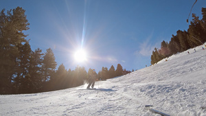 男子在雪坡上滑雪在山上的滑雪度假胜地由太阳背向下慢动作30秒视频