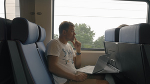 年轻男子在火车上乘车和手持笔记本电脑在桌子上对着窗户18秒视频