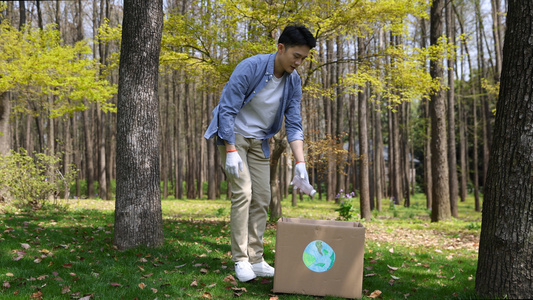 男生捡完塑料垃圾扔进垃圾箱并将垃圾箱抱走视频