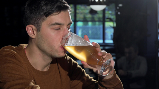 有吸引力的男人从酒杯里喝着美味的啤酒在酒吧放松视频