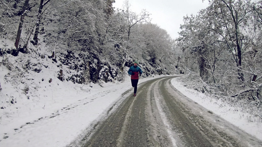 星期天早上在雪覆盖的乡村道路上穿着冬季夹克的男子在视频