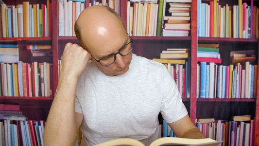 书架背景在家庭图书馆桌子上头顶着读书本的秃头人视频