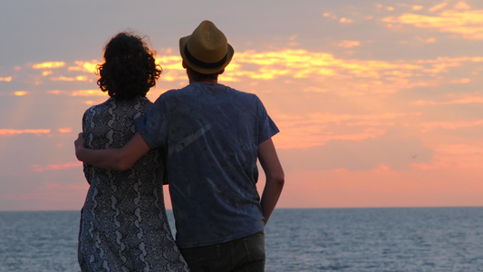 幸福恩爱的夫妻站在沙滩上拥抱享受日出的剪影视频