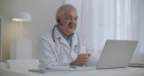 男医生通过笔记本电脑与同事或病人进行在线交流并使用视频