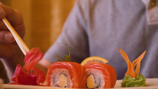 雄性在吃寿司卷时用红姜和木筷子拿红姜视频
