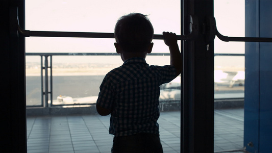 男孩从机场的窗外看着小男孩视频