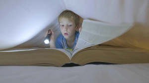 男孩子躲在被窝里看一本大书30秒视频