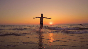 欢快的男孩双光环影奔跑的电影镜头日落时在沙滩上走出8秒视频