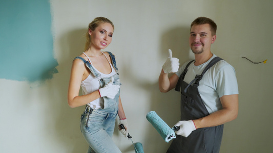 年轻夫妇家庭工人用滚滚机在公寓内油漆墙壁或视频
