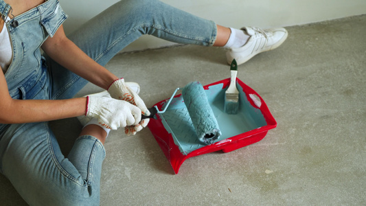 女工用桶装滚滚筒在公寓里油漆墙壁或视频