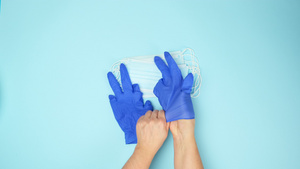 两只女手戴上蓝色乳胶手套戴上一次性医用口罩俯视流行病14秒视频