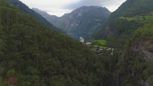 向前和向上飞过绿林山丘并显示在北北方有游轮的Geirangerfjord视频