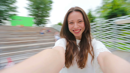 年轻女孩制作视频自拍并在公园里玩乐年轻积极的女人开心视频
