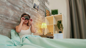 穿着睡衣的年轻女青年在眼睛上戴面罩睡觉27秒视频