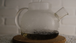 将沸水倒在黑茶壶的黑茶上白砖模糊背景旋转头晕灯光的32秒视频