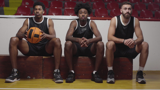 三个篮球运动员坐在一个板凳上观看比赛欢呼和鼓掌视频