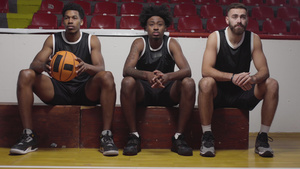 三个篮球运动员坐在一个板凳上观看比赛欢呼和鼓掌10秒视频
