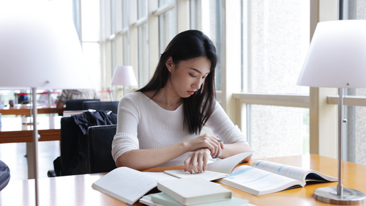 图书馆看书的女大学生在看时间视频